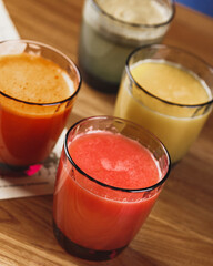 Wall Mural - Freshly squeezed juices in colored glass glasses on wooden table