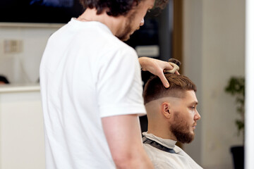 Wall Mural - Barber trim hair with clipper on handsome bearded man