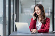 © crizzystudio - Beautiful Asian businesswoman using a smartphone to view social media applications, answer customer chats, transact through applications online job in an office.