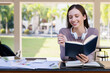 © skarie - Young female student with headphones reading and studying on teaxtbook at table in college.