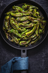 Pan Roasted Shishito Peppers on a black background. Top view. Low key photo.