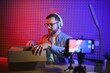 © Serhii - Fashion blogger recording video content, unboxing new sweater at home. Millennial influencer unpacking box with new clothes in front of professional camera, live streaming for social media.