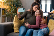 © Dorde - Beautiful pregnant single mother kissing her adorable little girl, holding smartphone, capturing precious moments, taking selfie or recording vlog for social media with her sweet child.