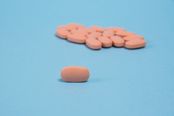 Wall Mural - Pink pill macro on a blue paper background and many pills in the background