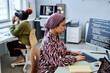 Side view portrait of Muslim young woman as software developer writing code and using computer in office
