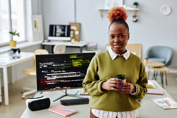 Waist up portrait of black young woman as software programmer smiling at camera in office, copy space