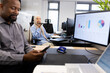 © WavebreakMediaMicro - Happy african american businessman with smartphone sitting at desk in office