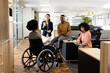 African american businesswoman on wheelchair and diverse people in office talking and laughing