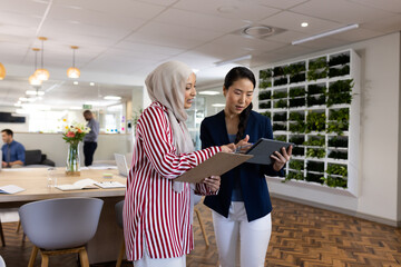 Wall Mural - Happy diverse businesswomen with tablets talking in office lounge