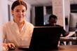 © DC Studio - Woman working on laptop in coworking space portrait, smiling employee typing on computer, looking at camera. Corporate worker planning business strategy, analyzing marketing report