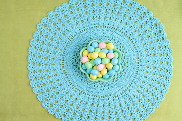 Sticker - Bowl of candy coated easter eggs on a pastel blue lace placemat
