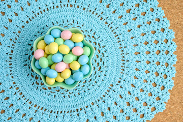 Sticker - Bowl of candy coated easter eggs on a pastel blue lace placemat
