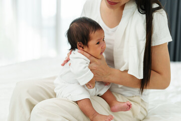 Wall Mural - mother holding newborn baby burping in bedroom after feeding milk