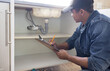 © Lumeez/peopleimages.com - Plumber, sink maintenance document and plumbing check of a handyman in a kitchen. Water pipe installation, home repair checklist and builder in a household for building construction and inspection