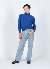 Wall Mural - Portrait isolated cutout studio full body shot of Asian young gay male model in turtleneck longsleeve shirt denim jeans with high heel leather shoes standing posing look at camera on white background