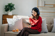 © laddawan - ￼Smiling girl relaxing at home, she is playing music using smartphone tablet, laptop, and wearing white headphones.
