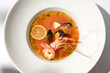 Traditional italian fish soup with shrimp, mussels and salmon. Seafood soup on white background. Tom yam kung with seafood. Spicy fish soup with prawns and lime on light background. Trendy food.