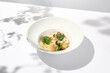 Seafood risotto with scallops and cauliflowers on white plate. Creamy risotto with sea scallops and cauliflowers. Italian risotto with sea scallops on light background with shadows of leaves