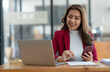 © Phimwilai - Beautiful asian businesswoman working with laptop computer is using mobile phone for talking. Finance business contacts in real estate projects in her office.