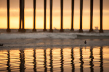 Support Poles Of The Pier Reflected On The Shoreline Of Huntington Beach At Sunset.