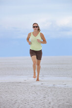 Woman Wearing Sunglasses Jogging Barefoot On The Utah Salt Flats