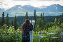 Female Hiker UsingÂ coin-operatedÂ binoculars, Alaska, USA