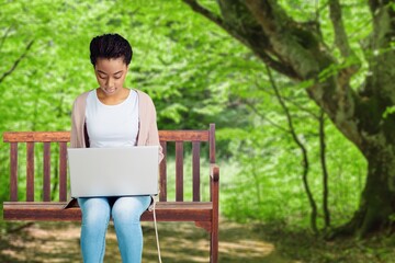 Creative young person works on laptop computer in park.