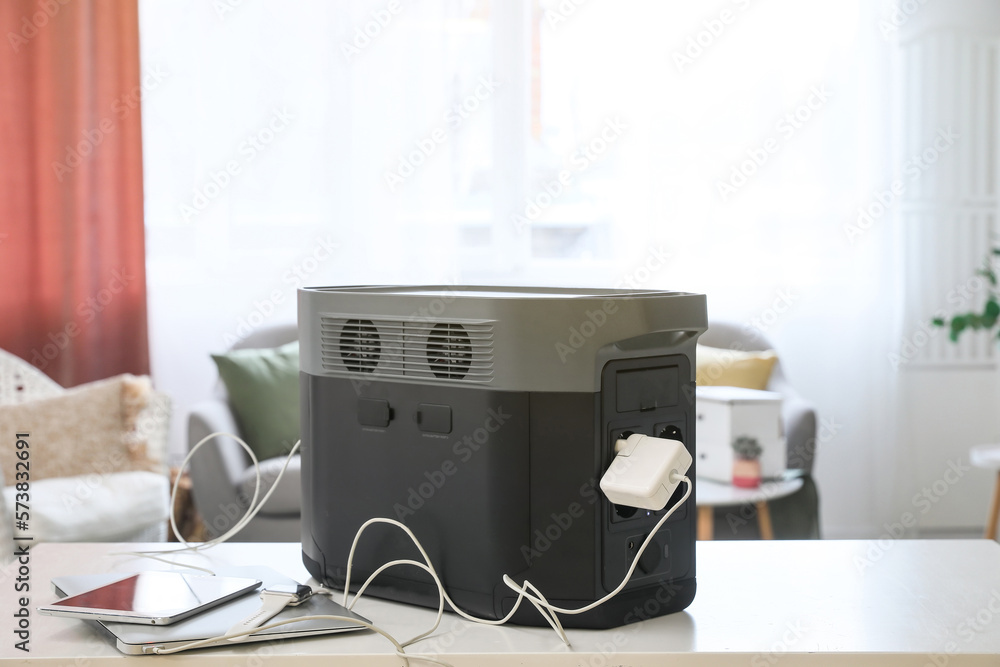Portable power station charging gadgets on table in living room