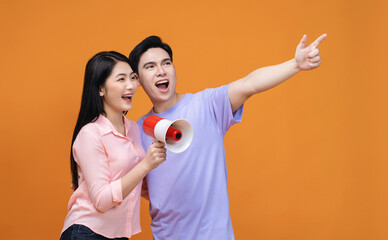 Young Asian couple with megaphone on background