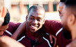 © Anela R/peopleimages.com - Sports, huddle and man athlete on a field for motivation or strategy planning with his team. Fitness, workout and happy African male rugby player talking with his sport group before a match or game.