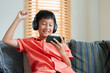Excited Asian boy playing online game on smart phone with headphones. 