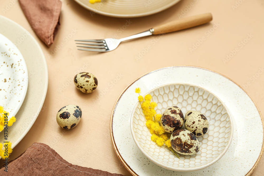Stylish table setting with Easter eggs and mimosa flowers on color background