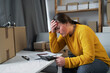 © Andrii Lysenko - Young woman working at small business ecommerce using laptop stressed and frustrated, surprised and angry face, sme bankruptcy, financial problem.