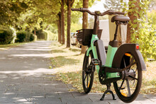 Bike Or Electric Bicycle For Rental Service In Green City. Urban Electro Bike Charging Battery In The Park. To Rent