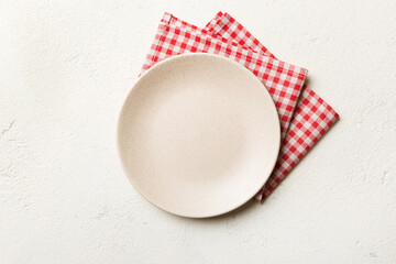 top view on colored background empty round white plate on tablecloth for food. empty dish on napkin 