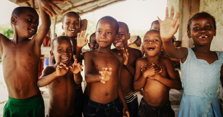 Wall Mural - A Group Of African Children, Laughing, Jumping And Waving in Rural Area. Black Kids Celebrating Life with Joy. Camera Captures Beauty and Essence Of Childhood, Innocence and Purity of Live in Village