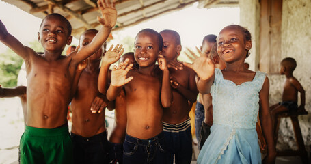 Wall Mural - A Group Of African Children, Laughing, Jumping And Waving in Rural Area. Black Kids Celebrating Life with Joy. Camera Captures Beauty and Essence Of Childhood, Innocence and Purity of Live in Village