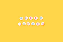 Hello Summer. Quote Made Of White Round Beads With Colorful Letters On A Yellow Background.