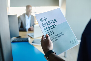 Poster - Close-up of young male economist holding mid-quarter report while standing by door of his boss office and going to enter