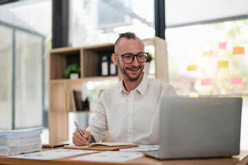 Wall Mural - Businessman using laptop computer in office. Happy middle aged man, entrepreneur, small business owner working online.