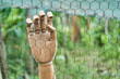 © ADDICTIVE STOCK - Wooden hand hanging on metal net