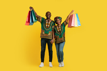 Happy african american couple in national costumes holding shopping bags