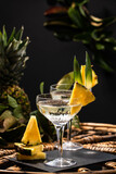 Fototapeta Uliczki - Champagne cocktail with pineapple decoration on a rattan table
