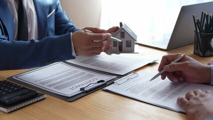 Wall Mural - Discussion With A Real Estate Agent, a businesswoman signing a contract for Insurance protecting house, a real estate home is pointing to insurance contract signing and are explaining to customers.