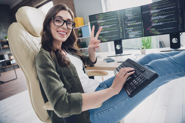 Wall Mural - photo of positive smiling lady freelancer wear eyeglasses showing v-sign working indoors workplace w