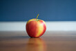 Photo of a red yellow apple laying on a table on a blue background