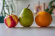 A pear, an orange and an apple laying upon a table