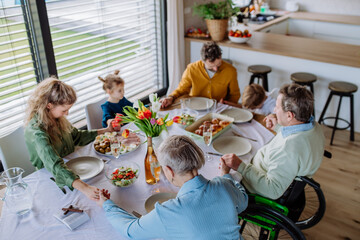 Wall Mural - Close-up of family holding hands, praying before Easter lunch.