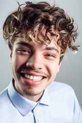 Happy smiling handsome man with mustache with curly hairstyle, wearing blue shirt, looking at camera