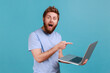 © khosrork - Man pointing finger at laptop with opened mouth and big eyes, expressing astonishment.